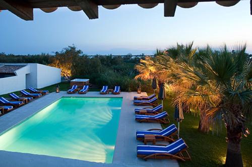 eine Gruppe von Liegestühlen und einem Pool in der Unterkunft Mangio Fango Hotel et Spa in Saintes-Maries-de-la-Mer