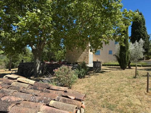 a stone wall in front of a house with a tree at Villa spacieuse avec jardin à Saignon in Saignon