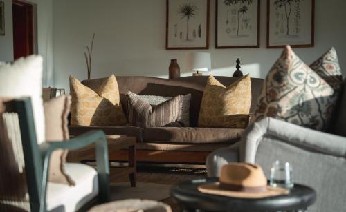 a living room with a brown couch with pillows at Kolokolo Safari Home - Mashatu Game Reserve in Lentswelemoriti