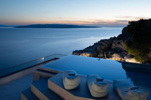 a swimming pool with chairs next to the water at Kuk Oaza Luxury Villas in Makarska