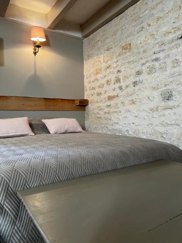 a bed in a room with a brick wall at Le Grenier d'Odette in Sainte-Gemme-la-Plaine