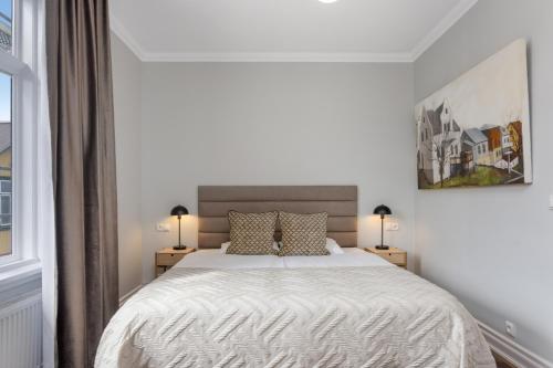 a white bedroom with a bed and two lamps at Berg Apartments in Reykjavík