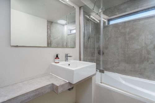 Un baño blanco con lavabo y ducha. en Villa Miau, en Sagres