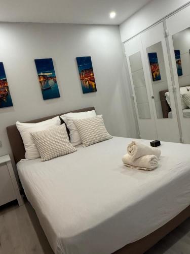 a bedroom with a large white bed with paintings on the wall at Appartement Valeria in Saint-Laurent-du-Var
