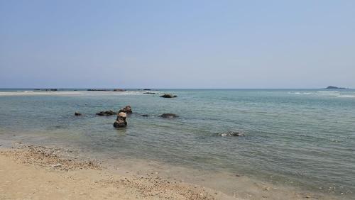 a person sitting in the water at the beach at Nilaveli house Stay in Kumpurupiddi