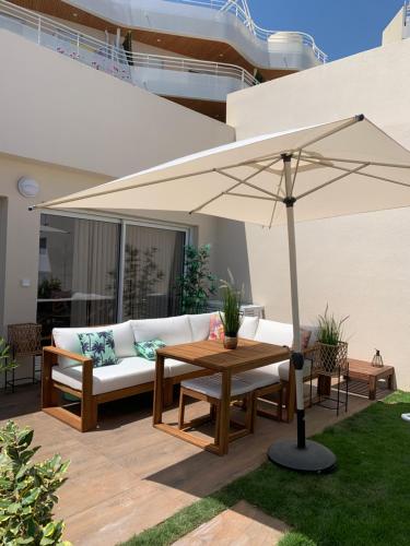 a patio with a white couch and an umbrella at Cap Neree Petit coin de paradis pieds dans l eau in Saint-Raphaël