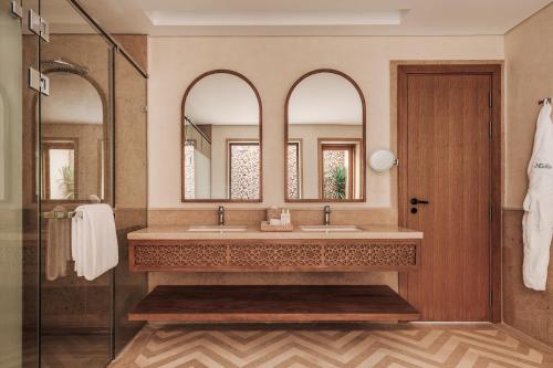 a bathroom with two sinks and two mirrors at Sakhra Hotel & Spa, Almaza Bay in Marsa Matruh