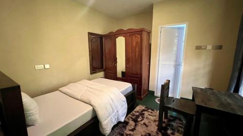 a small bedroom with two beds and a wooden cabinet at Skill forest lodge in Arusha
