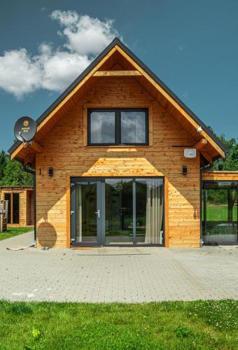 a wooden house with a large glass door at Domki Nad Stawami z Jacuzzi i Sauną 1 in Wolibórz
