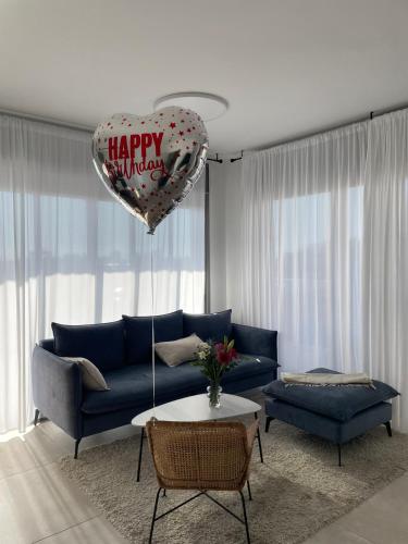 a living room with a blue couch and a heart balloon at luxury penthouse with a jaccuzi, pool and parking, suka for Sukkot optional in H̱olon