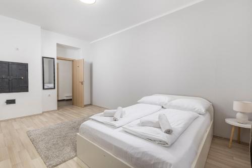 a white bedroom with a large bed with white sheets at Molo Longo - Downtown Apartments in Rijeka