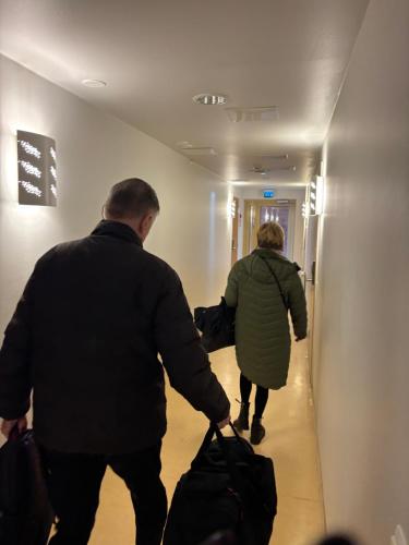 a man and woman walking down a hallway with luggage at Kraatterin Helmi Suite in Lappajärvi