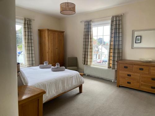 Schlafzimmer mit einem Bett, einer Kommode und Fenstern in der Unterkunft Town centre Victorian period 3 bedroom home in Bishops Castle