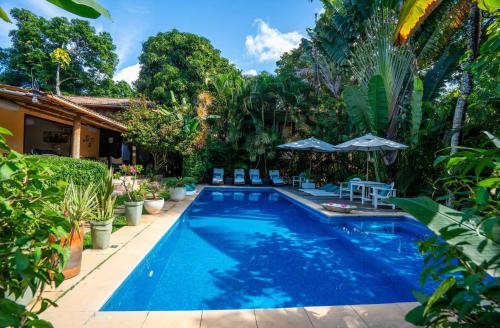 a pool with chairs and umbrellas next to a house at Pousada Jardim Das Margaridas in Trancoso