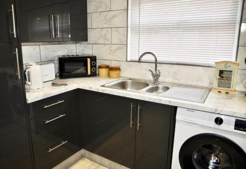 a kitchen with a sink and a microwave at The Great Escape by Tŷ SA in Newport