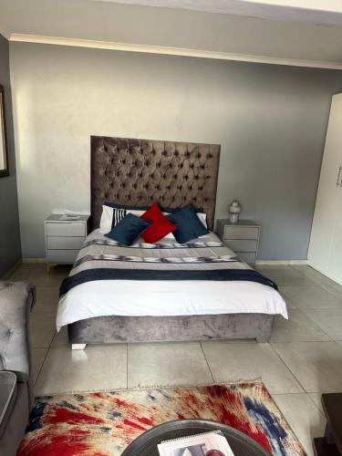 a bedroom with a large bed with blue and red pillows at Ubuntu Lifestyle Estate - Phalaphala DeLux in Krugersdorp