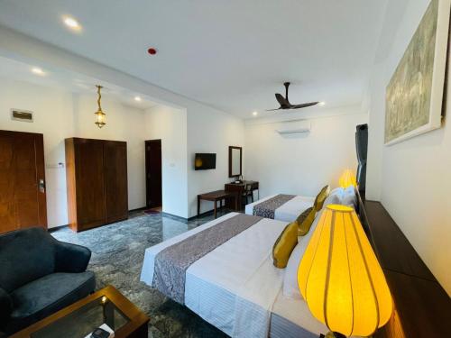 a hotel room with two beds and a couch at Mirage Kandyan Heights in Kandy
