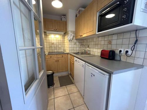 - une petite cuisine avec des placards en bois et un four micro-ondes dans l'établissement Appartement cosy 2 pièces, 6 couchages, proche pistes et commerces, La Salle-les-Alpes - FR-1-330F-214, à La Salle Les Alpes