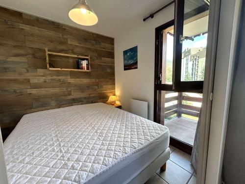 une chambre avec un lit et un mur en bois dans l'établissement Appartement cosy 2 pièces, 6 couchages, proche pistes et commerces, La Salle-les-Alpes - FR-1-330F-214, à La Salle Les Alpes