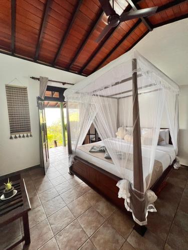 a bedroom with a bed with a canopy at Ambiente Guest House in Ella