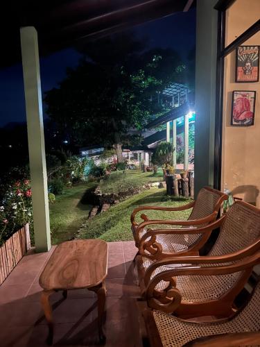 two chairs and a table on a porch at night at Ambiente Guest House in Ella