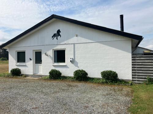 a white building with a horse on the roof at Lejlighed i naturskønt område in Bratten Strand
