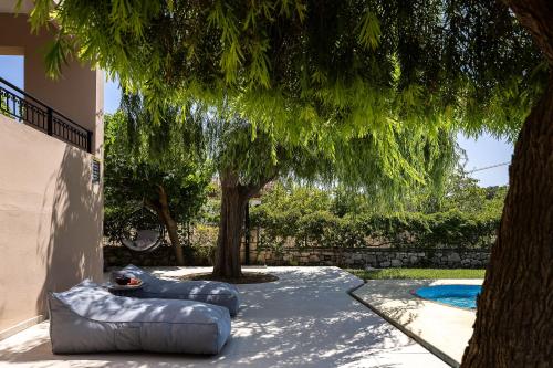 a backyard with two inflatablelatable chairs under a tree at Villa Lambros in Roústika