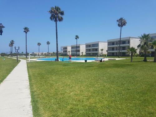 a swimming pool in a park with palm trees at Ola Blanca in Dar Hamida