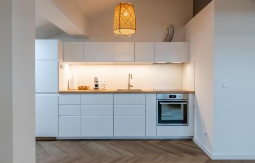 a kitchen with white cabinets and a sink at Griunvaldo apartamentai in Kaunas