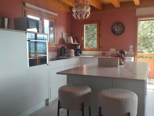 a kitchen with red walls and a counter with stools at Chalet Taninges in Taninges