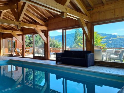 a house with a pool with a couch and windows at Chalet Taninges in Taninges