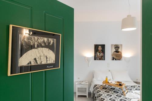 a bedroom with a green wall with a bed and pictures at Birbas Hotel in Agia Anna Naxos