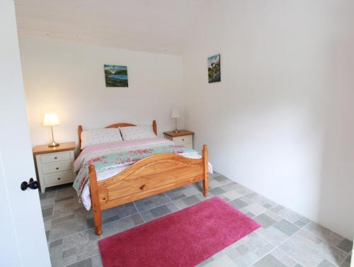 a bedroom with a bed and a pink rug at Kate's Cottage in Louisburgh
