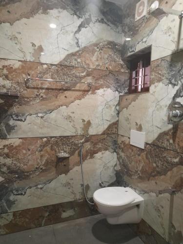 a bathroom with a toilet and a stone wall at ARONIC beach hotel in Varkala