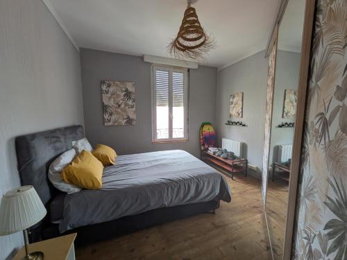 une chambre avec un lit avec des oreillers jaunes et une fenêtre dans l'établissement Appartement charmant dans le centre de Biarritz Dan 3ème étage, à Biarritz