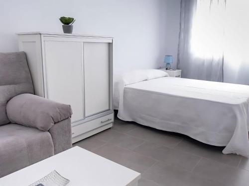 a white bedroom with a bed and a couch at Estudio centrico y economico en Conil in Conil de la Frontera