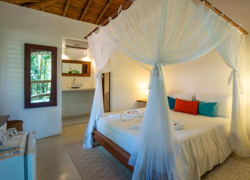a bedroom with a bed with a mosquito net at Pousada Jardim Das Margaridas in Trancoso