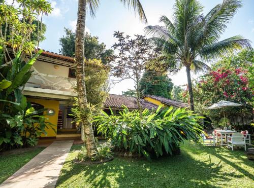 a house with a garden and palm trees at Pousada Jardim Das Margaridas in Trancoso