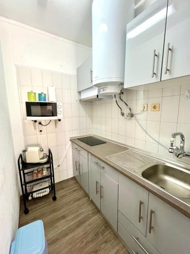 a kitchen with white cabinets and a sink at Casa da Praia na Torre Castelo in Armação de Pêra