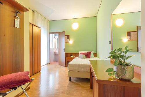 a hotel room with a bed and a desk and a room at Hotel Terme Paradiso in Abano Terme