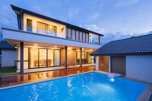 a house with a swimming pool in front of a house at Ma-Umi Chiang Mai pool villa 5 BRs - 10 mins to city center and Airport in Chiang Mai