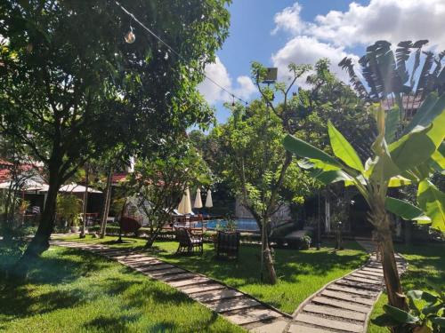 a garden with trees and chairs and a pool at Banksy's Siem Reap in Phumĭ Réach Born