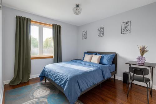 a bedroom with a bed and a table and a window at Newly Renovated 3BR North York Bungalow with Backyard Patio & Volleyball Set! Close to Rogers Stadium, TTC Subway Access, Perfect for Family Travel, Group Trips or Work Stays! in Toronto