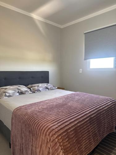 a bedroom with a bed with a striped blanket and a window at Apartamento Exclusive in Araçatuba