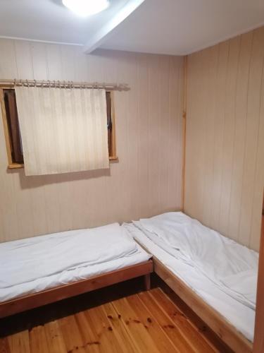 two beds in a small room with a window at Amber Coast - Domek nr 4 in Jantar