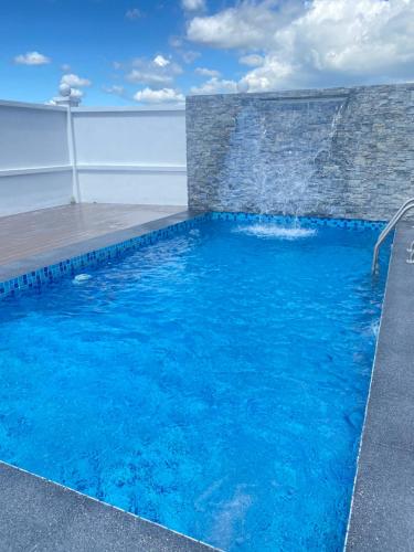 a blue swimming pool with a water fountain at Calma Villa Hutan Kampung in Alor Setar