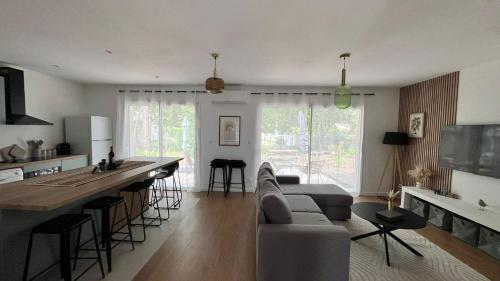 - une cuisine et un salon avec un canapé et un bar dans l'établissement Villa Oyat entre foret et océan, à Grayan-et-lʼHôpital