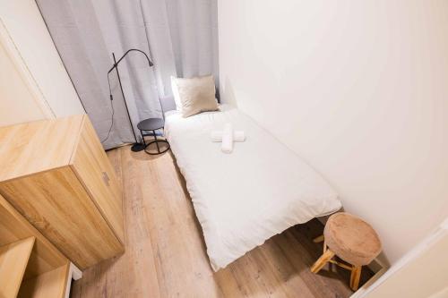 a small bedroom with a white bed and a stool at Stylish 50m2 Two-Bedroom Apartment - SD23K in Eindhoven