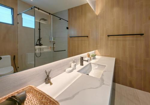 une salle de bain avec un lavabo blanc et une douche dans l'établissement Bangtao Luxury Pool Villa - PrymaVerde, à Laguna Phuket