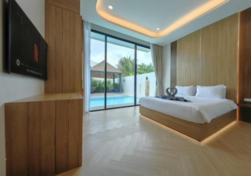 - une chambre avec un lit, une télévision et une piscine dans l'établissement Bangtao Luxury Pool Villa - PrymaVerde, à Laguna Phuket